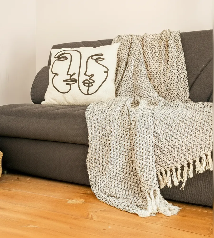 Il divano letto grigio del soppalco con il plaid, il cuscino decorato e il cesto in vimini
